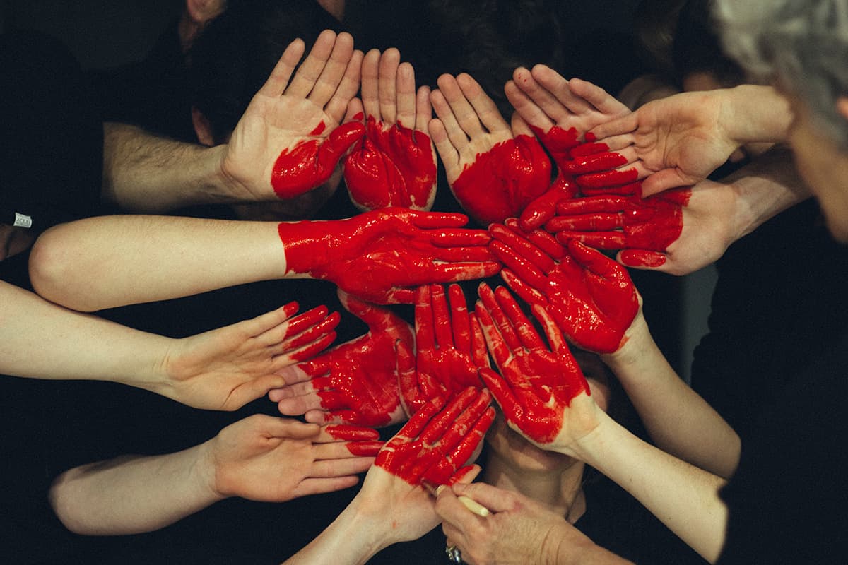 Manos pintadas de rojo en forma de corazon mostrando unidad